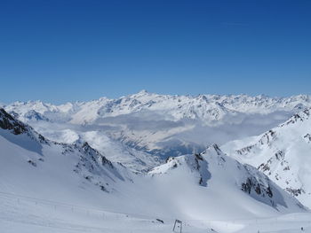 Scenic view of snowcapped mountains against clear blue sky