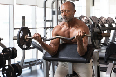 Shirtless man lifting weights in gym