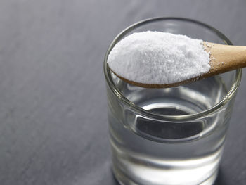 Close-up of powdered sugar with water in drinking glass on table