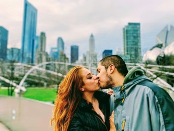 Couple kissing against cityscape in background