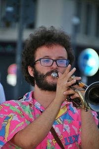 Close-up portrait of young man wearing eyeglasses playing trumpet