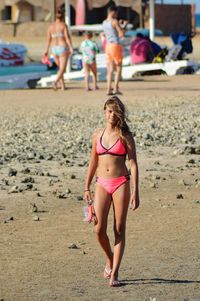 Full length portrait of girl wearing swimwear while walking at beach