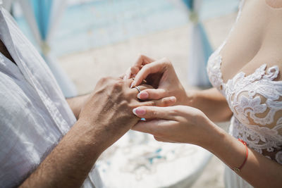 Midsection of bride and bridegroom holding hands