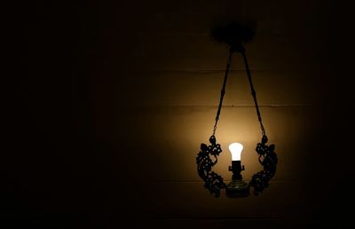 Low angle view of illuminated light bulb hanging at night