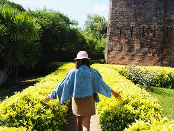 Rear view of woman walking on flowering plants