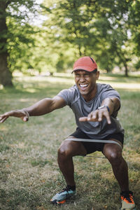 Determined man practicing squats on grass at park