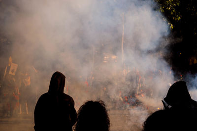 Rear view of silhouette people by firework display on road 