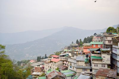 High angle view of town on hill against mountain during foggy weather