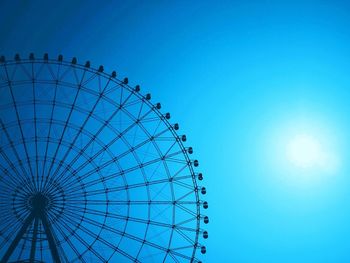 Low angle view of ferris wheel against blue sky