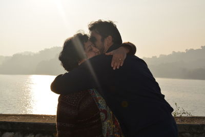 Man hugging mother at riverbank