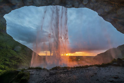 Scenic view of waterfall against sky during sunset