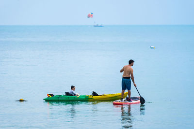 Rear view of men on sea against sky