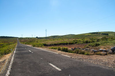 Road leading towards landscape against clear sky