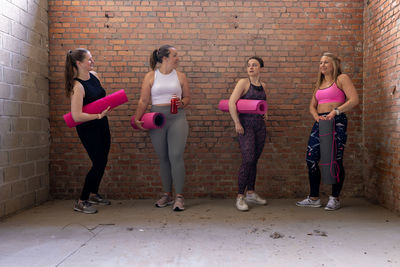 Full length of friends standing against wall