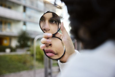 Young woman reflecting in hand mirror