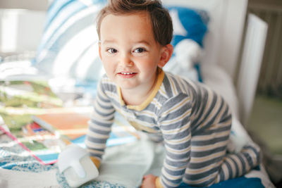 Cute adorable caucasian kid boy sitting on bed drinking milk from kids bottle. healthy eating 