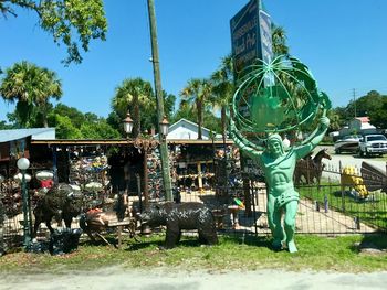 View of sculpture and palm trees against sky