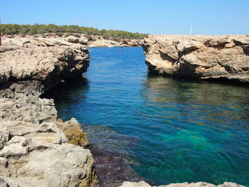 Rock formation in sea against clear sky