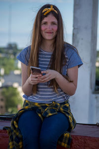 Portrait of smiling girl using mobile phone outdoors