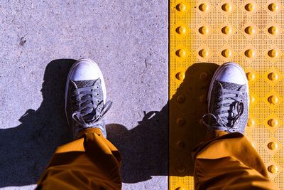 Low section of person standing against yellow wall