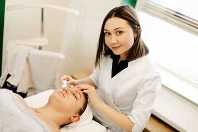 Portrait of a cosmetologist girl doing massage with a gouache scraper to a client. facial massage