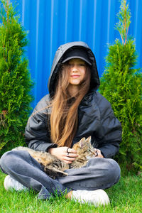 Portrait of young woman standing against plants.