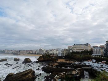 Buildings in city against cloudy sky