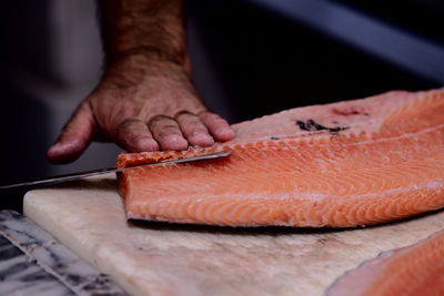 Close-up of man cutting fish on cutting board