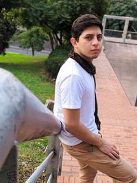 Portrait of young man standing by railing