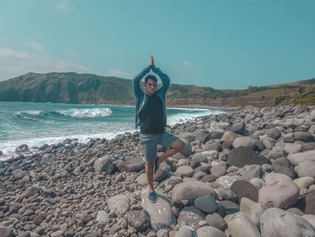 Full length of young woman on rocks at beach