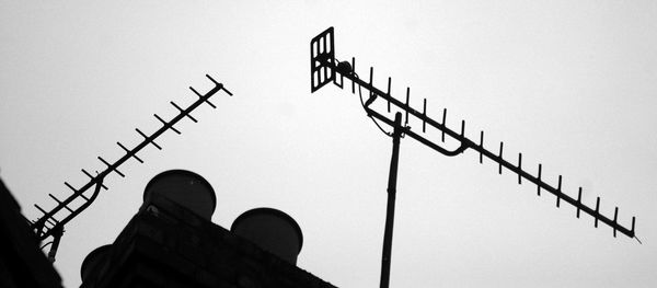 Low angle view of silhouette smoke stacks and television aerial