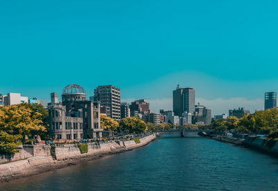 Canal amidst buildings against clear blue sky