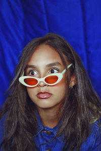Close-up of teenage girl wearing sunglasses while looking away against curtain