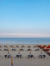 People at beach against clear blue sky