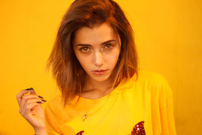 Portrait of young woman with brown hair against yellow background