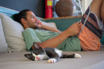 Cat and man resting on bed at home