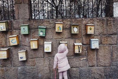 Rear view of woman standing against wall