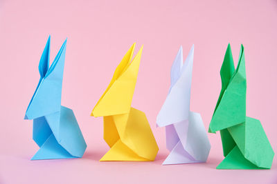 Paper colorful origami esater rabbits on pink background. easter celebration concept
