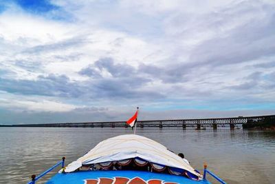 Boats in sea against cloudy sky