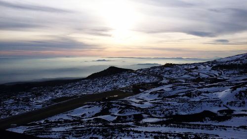 Scenic view of snow covered field against cloudy sky