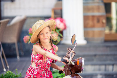 Portrait of smiling young woman wearing hat standing outdoors