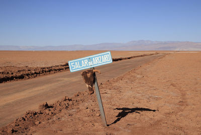 Information sign on desert against clear sky