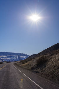 Road by mountains against clear sky