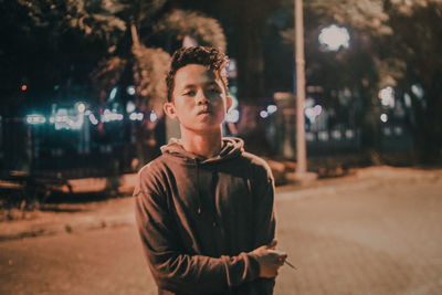 Portrait of young man standing in city at night