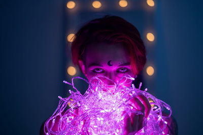 Portrait of man holding illuminated light