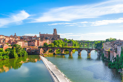 Bridge over river amidst buildings against sky