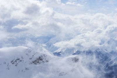 Aerial view of snow covered mountains against cloudy sky