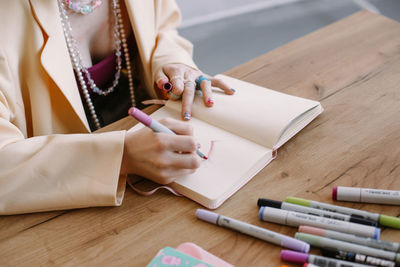 Midsection of woman writing in book