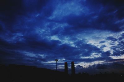 Silhouette of water tower against cloudy sky