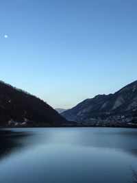 Scenic view of lake and mountains against clear blue sky